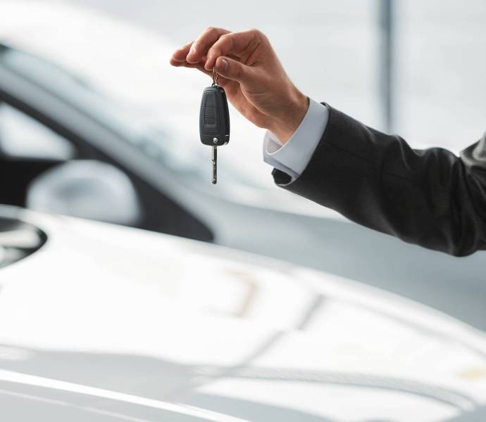 Car sales Car salesman is standing at the dealership holding a keys. Close-up.